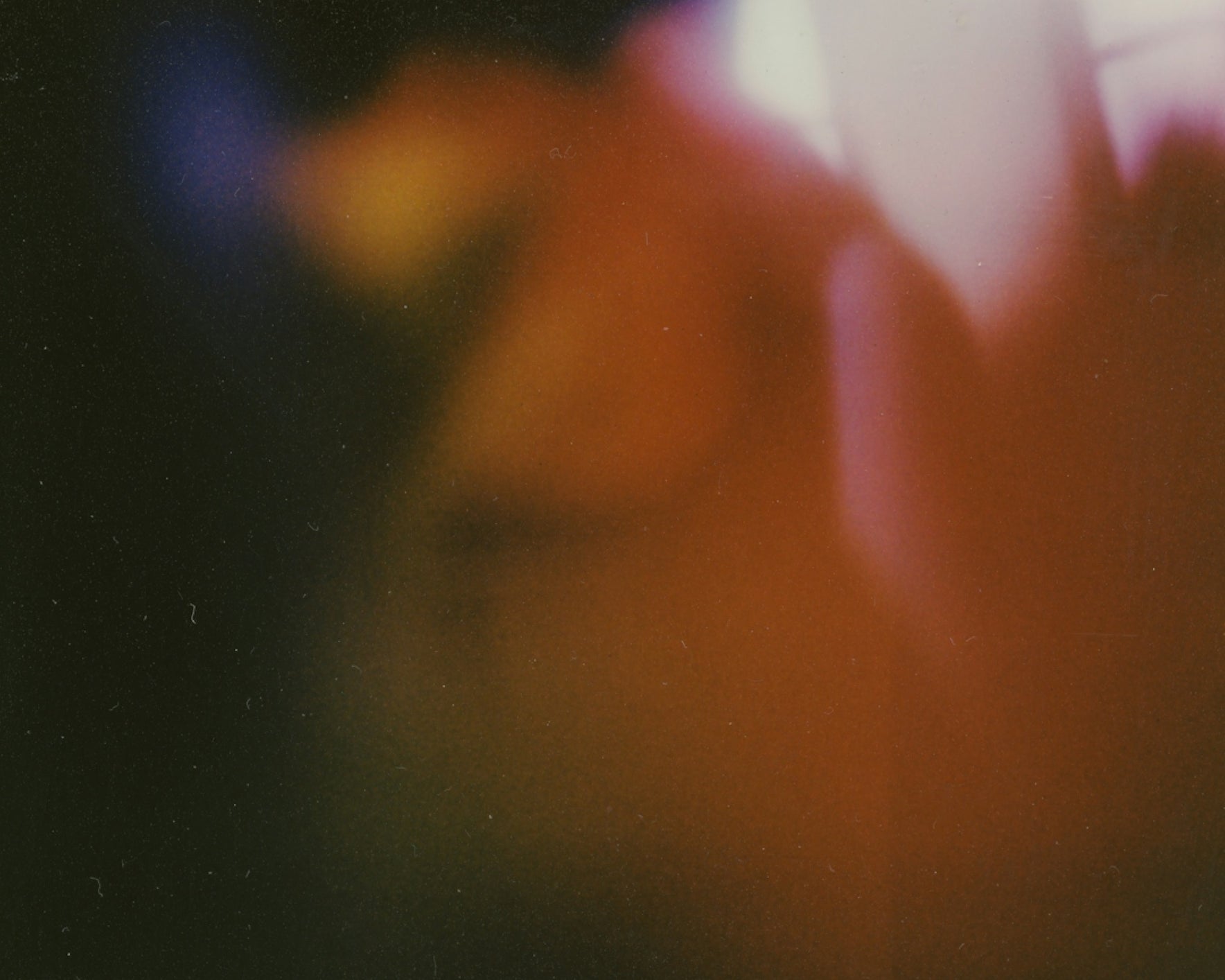 A soft, abstract image with a mix of dark and warm tones, featuring a gradient of orange, red, and purple hues blending together.