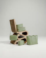 A minimalist wooden chair is styled with Metro Tote, Metro Crossbody Large Metro Toiletry Case, and Compressible Packing Cubes in Cactus.