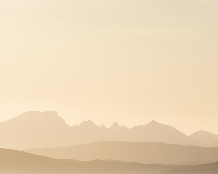 Soft silhouettes of distant mountains blend into a pale, hazy horizon, with gentle layers of hills fading into the background.