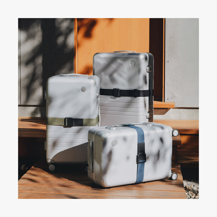 Ocean Blue | Front view of three Aluminum suitcases displaying all three Luggage Strap colors
