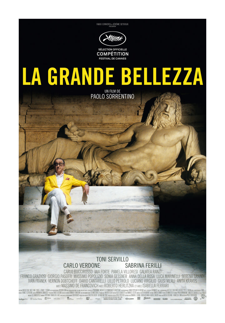 A movie poster for La Grande Bellezza showing a man in a yellow jacket sitting against an ancient statue, highlighting a scene from the Italian film.