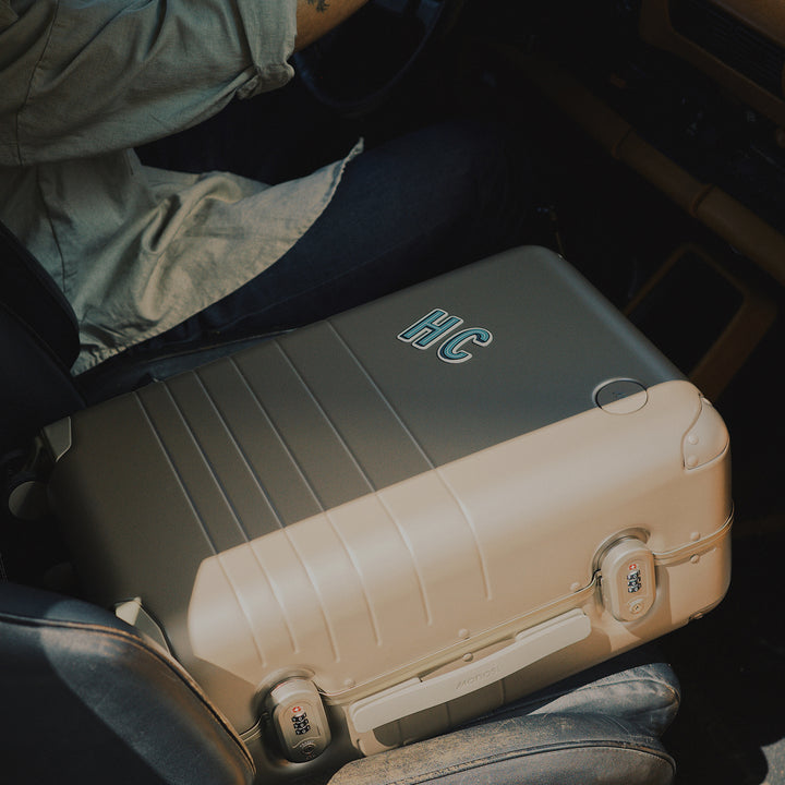 Two suitcases with 'HC' stickers on a vehicle seat