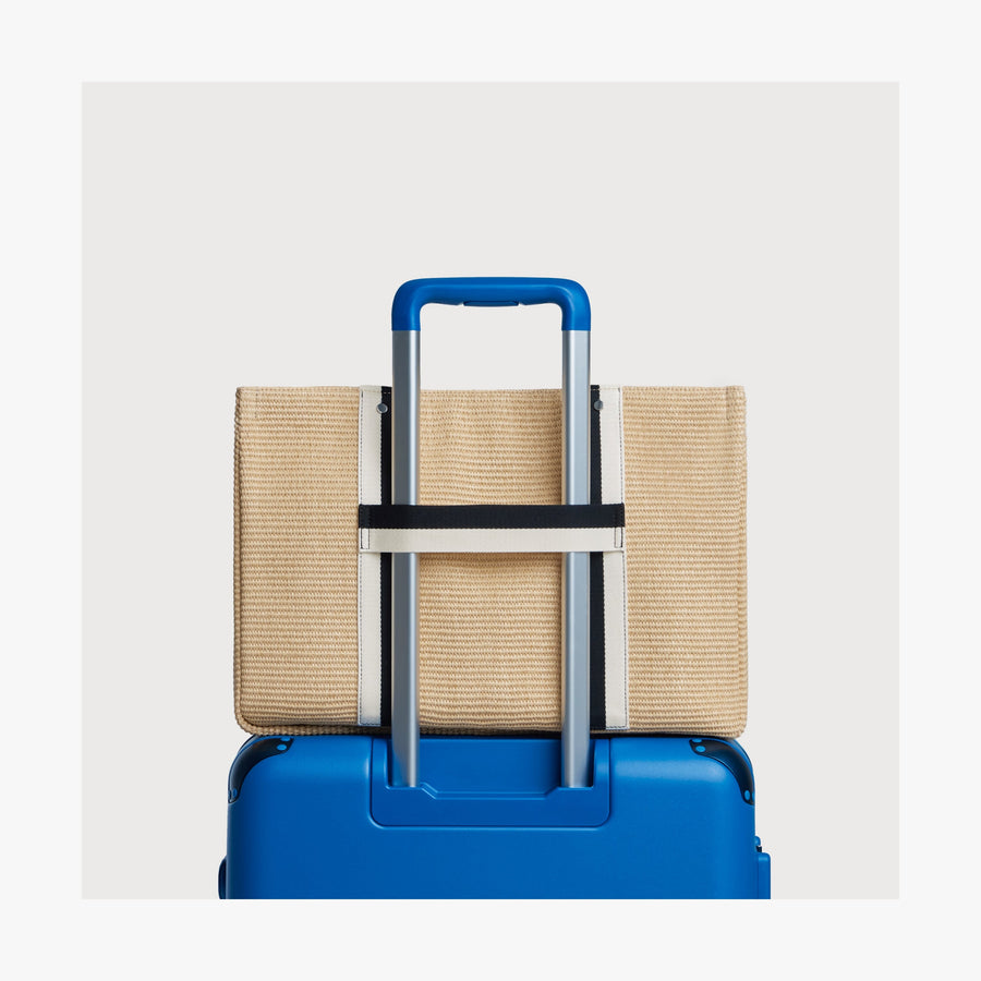 Natural | Canopy Tote securely placed over the telescopic handle of a Coastal Blue suitcase