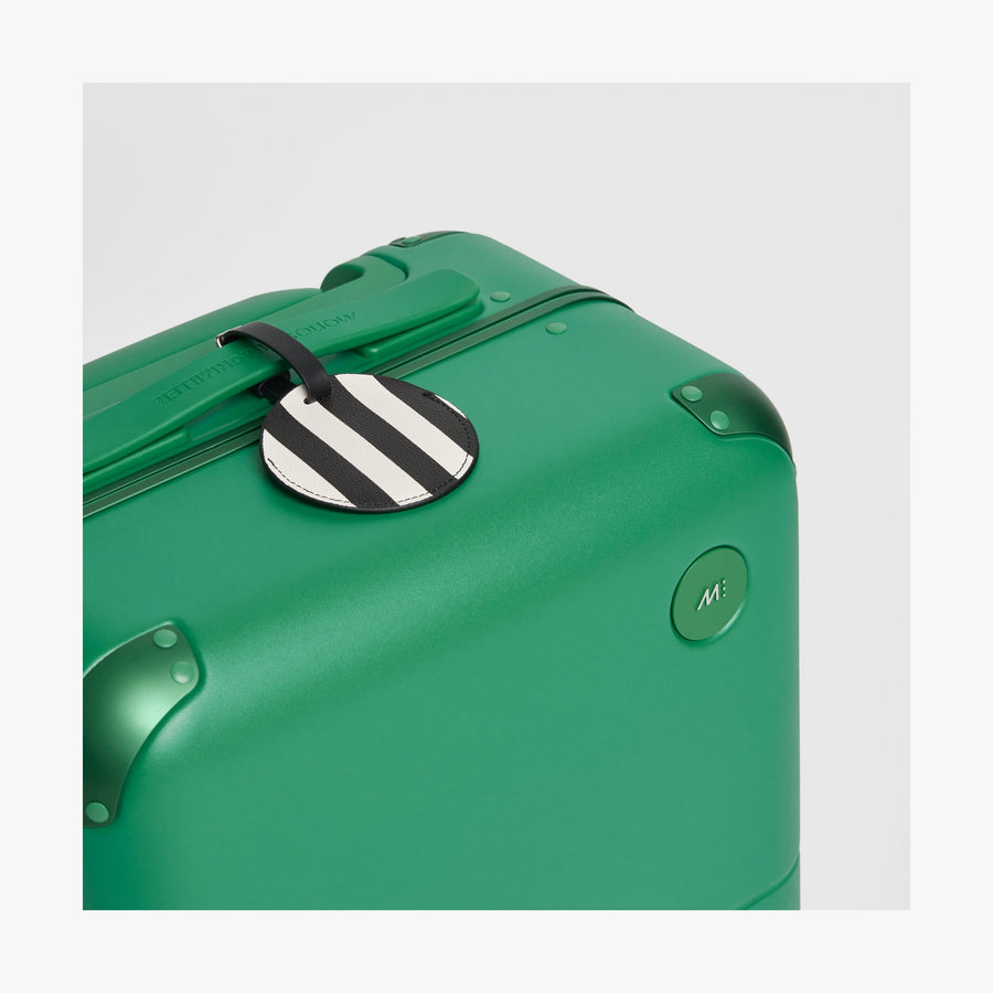 Jungle Green | Close-up view of the logo detail on a Hybrid suitcase in Jungle Green, paired with a Poplin Stripe Black Jungle Green luggage tag