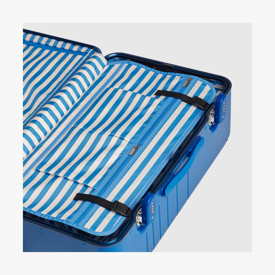 Coastal Blue | Interior view of a Hybrid suitcase in Coastal Blue featuring the Poplin Stripe Coastal Blue compression pad with adjustable straps