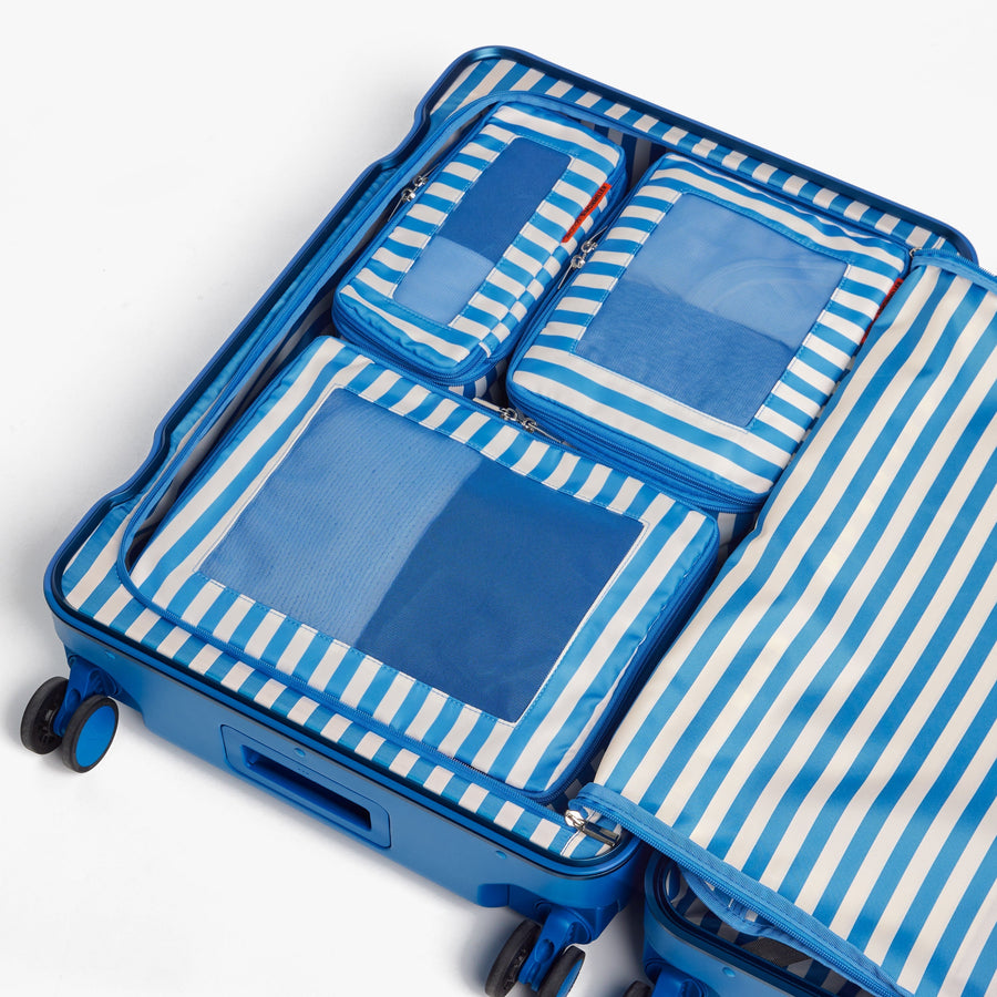 Set of Four / Poplin Stripe Coastal Blue | Poplin Stripe Coastal Blue compressible packing cubes neatly organized inside a Coastal Blue suitcase