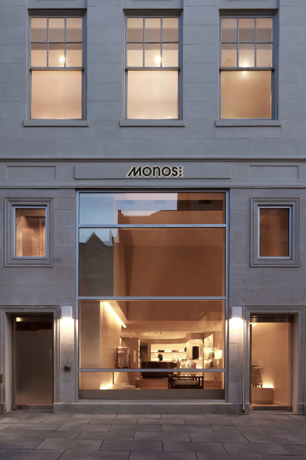 Monos Boston store exterior on Newbury Street, with large glass windows and minimal stone façade.