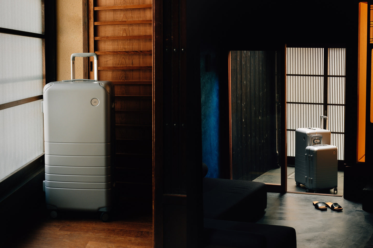 Three Hybrid suitcases in silver positioned in a serene, traditional Japanese-style interior. A hybrid trunk and hybrid carry-on in silver are near an open doorway, reflecting soft natural light from outside, while one hybrid trunk in silver stands alone near a wooden screen. The contrast between the minimalist luggage design and the warm wooden tones of the setting creates a harmonious blend of modernity and tradition.