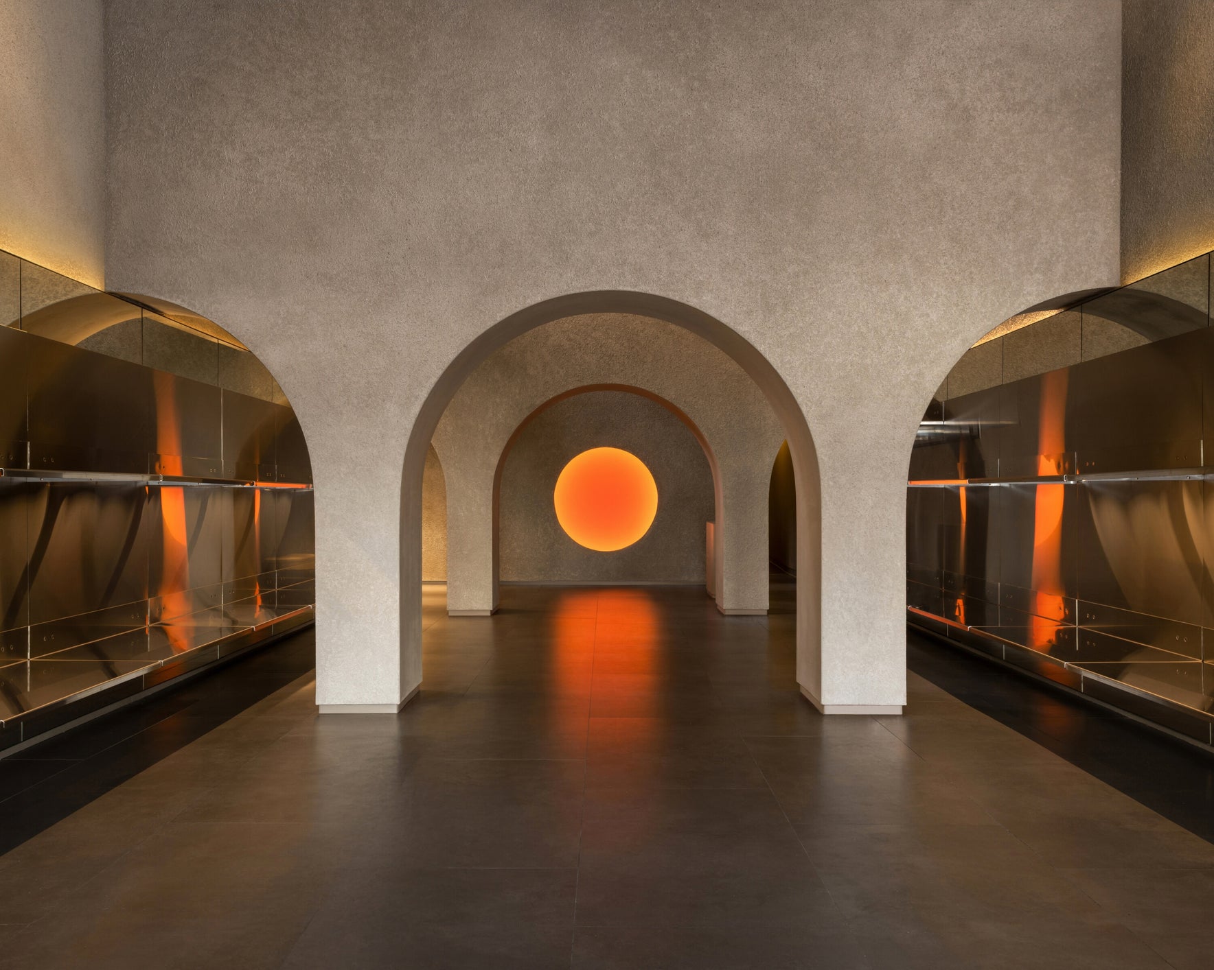 Monos Georgetown store interior with arched architecture, stainless steel shelving, and a glowing circular light centerpiece.