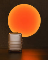 Aluminum luggage displayed beneath a glowing circular light feature inside the Monos Georgetown store, highlighting the brand’s minimalist design and warm, architectural lighting.