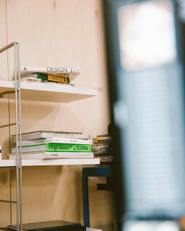 Close-up of bookshelves stacked with design books, including a prominent title on Virgil Abloh’s work. The curated selection of books emphasizes a dedication to iconic and modern design.