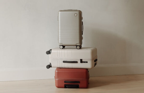 Hybrid Carry-On in Champagne, Carry-On in Desert Taupe, and Carry-On in Terracotta are stacked on top of each other against a neutral coloured background.