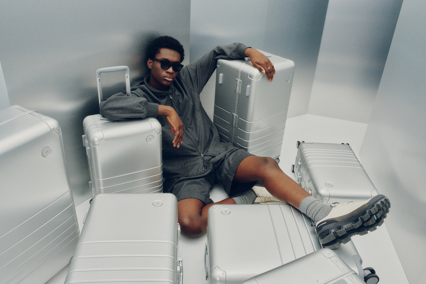 A model in dark tones reclines among the Monos Aluminum Collection in Aspen Silver.
