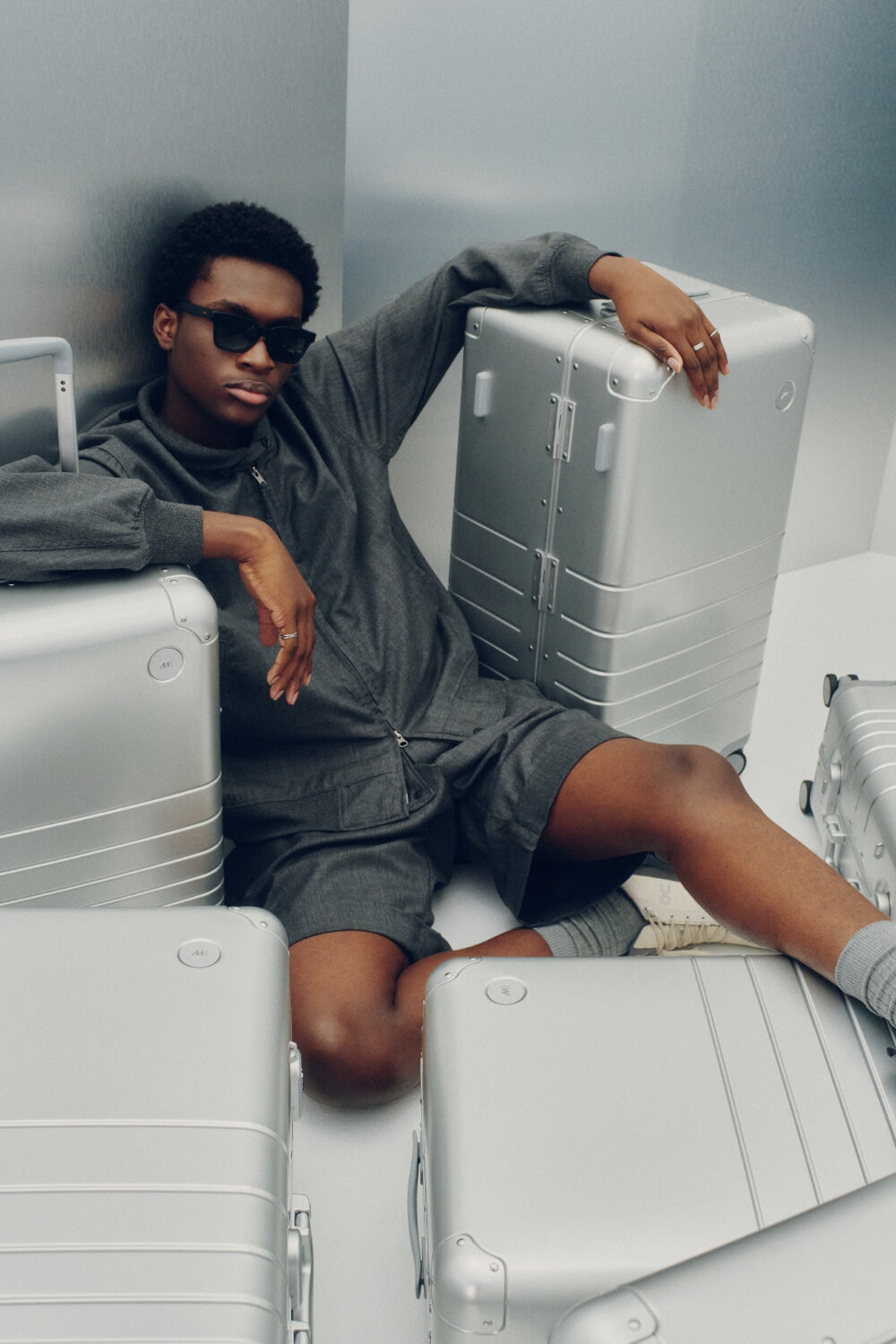 A model in dark tones reclines among the Monos Aluminum Collection in Aspen Silver.