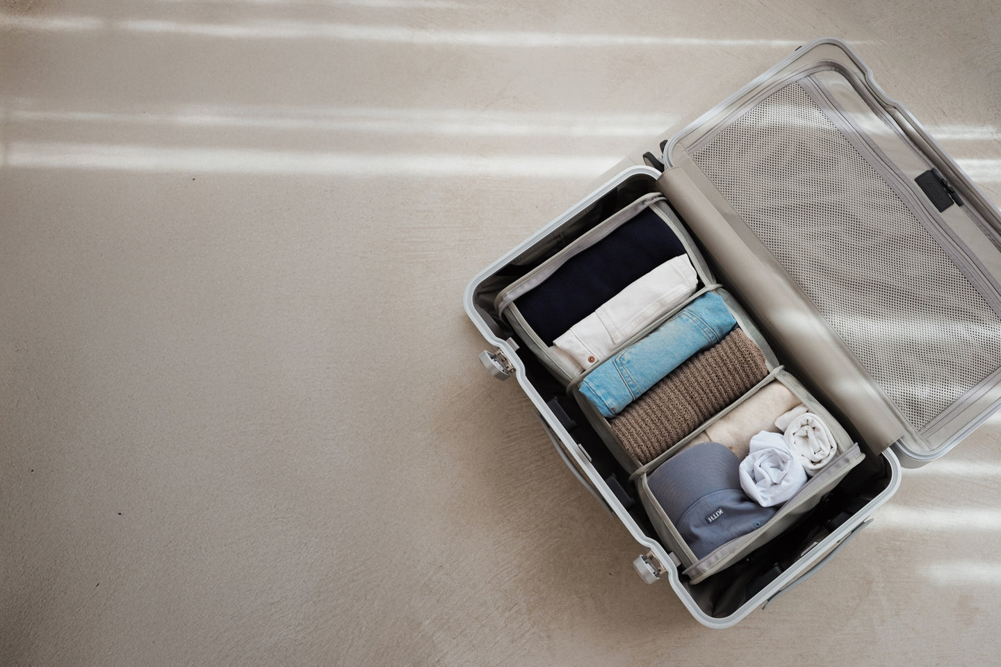 An open suitcase neatly packed with the Packable Hanging Closet, showcasing a well-organized selection of rolled and folded essentials under soft natural light.