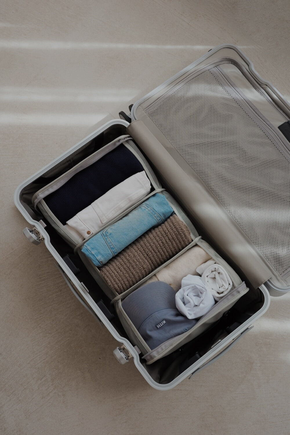 An open suitcase neatly packed with the Packable Hanging Closet, showcasing a well-organized selection of rolled and folded essentials under soft natural light.