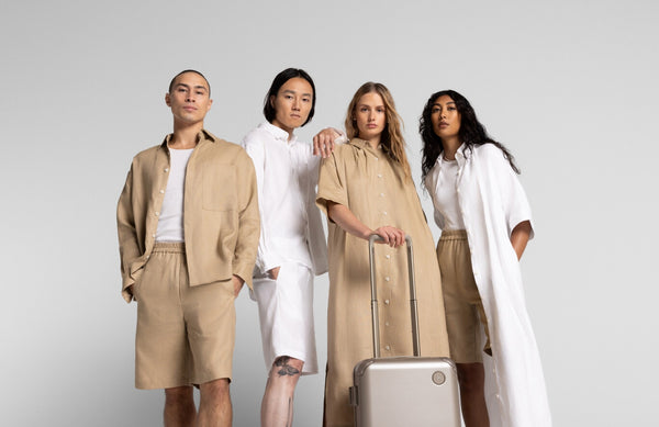 A group of four models, dressed in Algarve collection stands confidently with a Hybrid Carry-On in Champagne.