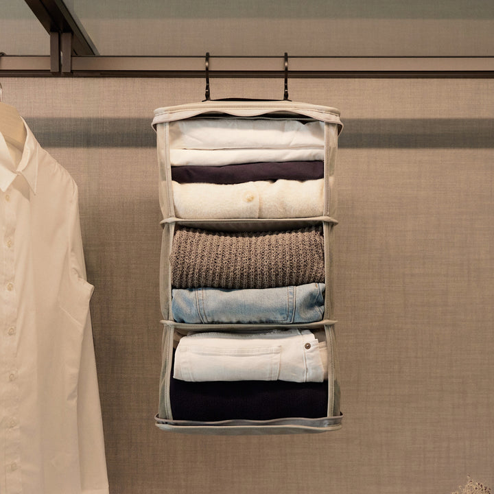 The Packable Hanging Closet fully expanded and neatly organized, hanging beside a crisp white shirt in a refined, neutral-toned wardrobe.