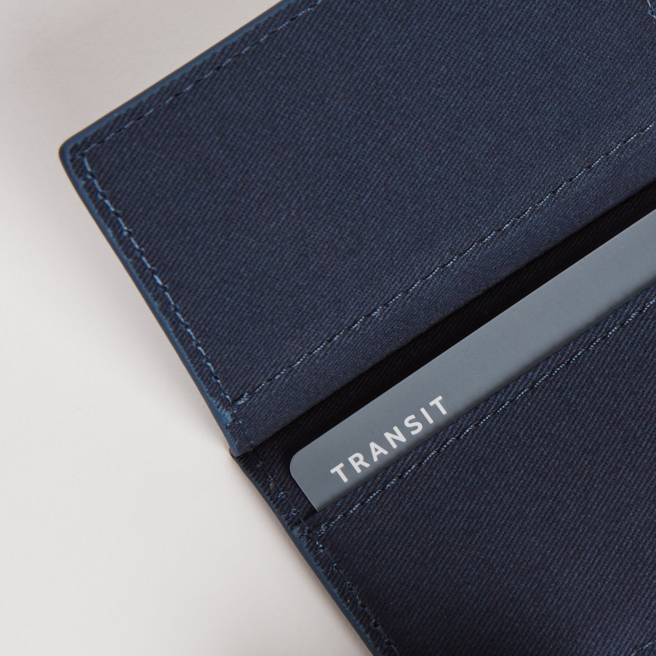 A close-up of the interior of a slim wallet in oxford blue with a transit card partially visible in one of the slots, showcasing the functional card storage.