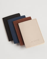 A lineup of four slim wallets in various colors—carbon black, oxford blue, mahogany, and ivory—displayed to highlight the color options and craftsmanship.