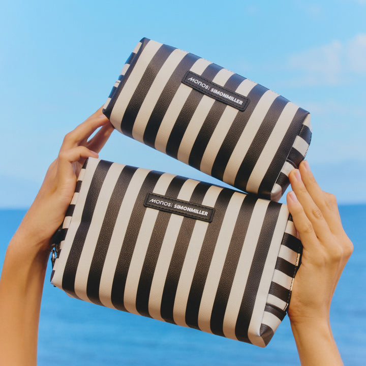Two black and white striped bags held by hands against a blue sky.