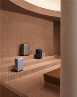 Luggage displayed on terracotta brick steps inside the Monos SoHo store, framed by warm light and curved architectural lines.