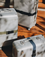 Monos luggage with Luggage Straps in Olive Green, Ocean Blue, and Midnight Black under natural sunlight.