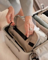 A close-up of hands unclipping the Packable Hanging Closet from a suitcase, revealing neatly packed essentials in a streamlined travel setup.