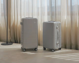 The Hybrid Trunk and Trunk Medium suitcases in Silver, side by side in soft morning light, set against sheer curtains in a serene, minimalist space.
