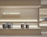 Monos Classic Collection luggage displayed on illuminated shelving inside the Boston store.