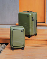 Monos Carry-On Pro and Expandable Carry-On in Olive Green on wooden steps.